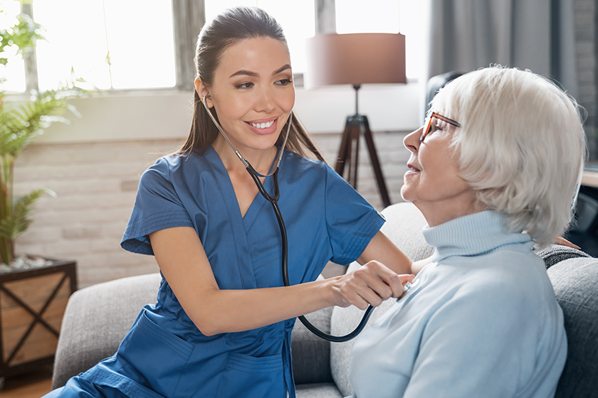 Caring nurse using stethoscope while examining retired woman 